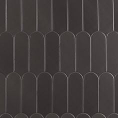 a black tile wall with rows of oval shapes