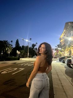 a woman is standing on the sidewalk at night