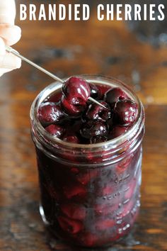 a jar filled with cherries on top of a wooden table