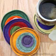 a stack of multicolored coasters next to a cup of coffee on a wooden table