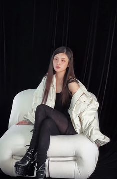 a woman sitting on top of a white chair wearing black stockings and high heeled boots