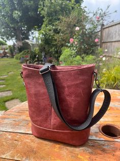 Leather Bucket Bag in deep red leather with black adjustable strap in black leather for crossbody or over shoulder. A beautiful deep red leather bag. Fully lined with a jungle themed print cotton lining. Zip top closure for security with an additional  interior zip pocket  . This lovely leather bag has an oval base that will accommodate most things, and has an adjustable black  leather strap enabling  it to be worn over the shoulder or across the body. The contrast top stitching is in a rainbow Burgundy Bucket Bag For Travel, Burgundy Leather-lined Crossbody Shoulder Bag, Burgundy Leather Lining Crossbody Shoulder Bag, Burgundy Leather Crossbody Shoulder Bag, Burgundy Bucket Shoulder Bag For Everyday, Burgundy Shoulder Bag With Adjustable Strap, Red Leather Bucket Bag For On-the-go, Burgundy Bag With Adjustable Strap For On-the-go, Burgundy Crossbody Satchel With Adjustable Strap