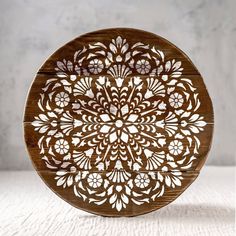 a wooden plate with an intricate design on the front and sides, sitting on a white surface