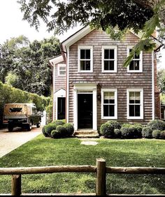 a truck parked in front of a gray house with white windows and two large doors