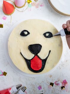 a cake decorated with a dog's face and tongue is being cut by a knife