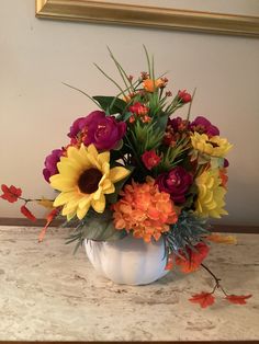 a white vase filled with lots of colorful flowers