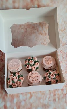 cupcakes in a white box with pink frosting and roses on them, sitting next to each other