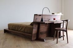 a bed sitting on top of a hard wood floor next to a desk with a lamp