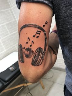 a man's arm with headphones and music notes tattooed on the side of his arm