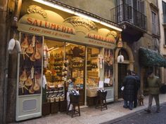 two men walking past a store on the side of a street in an old european city