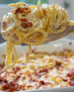 a spoon full of pasta and cheese being lifted from a casserole dish