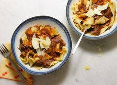 two bowls filled with pasta and meat on top of a table