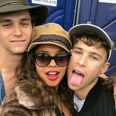 three people with their tongue out posing for a photo in front of a blue bus