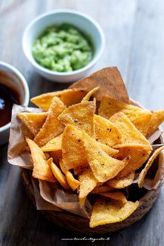 tortilla chips with salsa and guacamole in small bowls on a wooden table