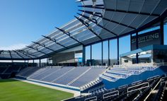 an empty stadium filled with blue seats under a clear roof over looking the grass and water