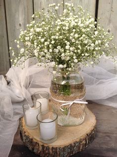 a vase filled with white flowers sitting on top of a wooden table next to candles