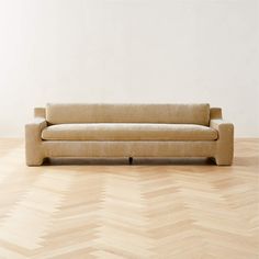 a green couch sitting on top of a wooden floor next to a white wall in an empty room