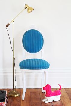 a blue and white chair sitting next to a lamp on top of a hard wood floor