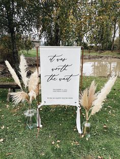 a sign that is sitting in the grass with some flowers and feathers on top of it