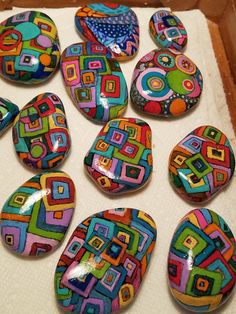 many colorful rocks are in a box on the floor and one is painted with different colors