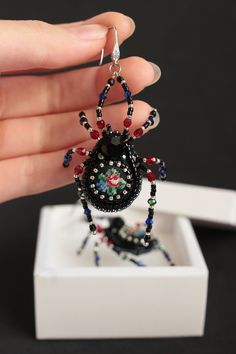 a hand holding a black beaded spider charm with red, white and blue beads