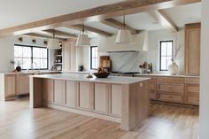 a large kitchen with wooden floors and white walls, along with an island in the middle