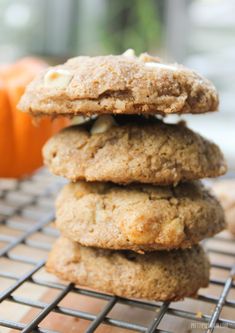 a stack of cookies sitting on top of a cooling rack next to an orange pumpkin