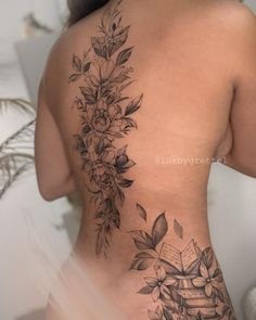 a woman's back tattoo with flowers and books on her left side ribcage