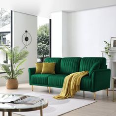 a living room filled with furniture and a green couch in front of a large window