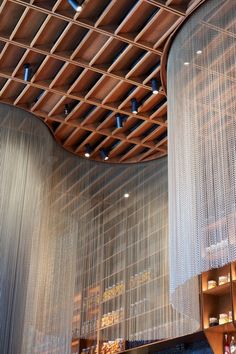 the inside of a building with wooden ceiling and metal mesh curtains hanging from it's sides