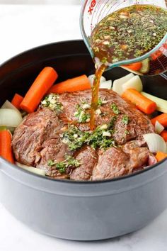 someone is pouring sauce on some meat and vegetables in a pot with the carrots