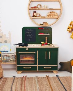 a child's play kitchen with an oven and shelves on the wall behind it