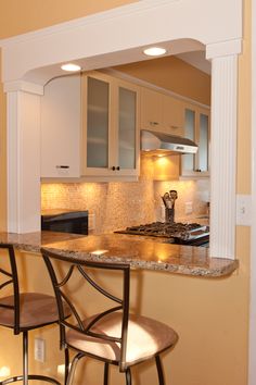 a kitchen with two bar stools next to the counter