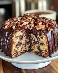 a cake with chocolate frosting and pecans is cut in half on a plate