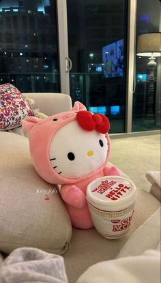 a hello kitty doll sitting on top of a couch next to a bowl of yogurt