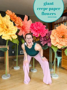 a woman posing in front of giant paper flowers with the words giant crepe paper flowers above her