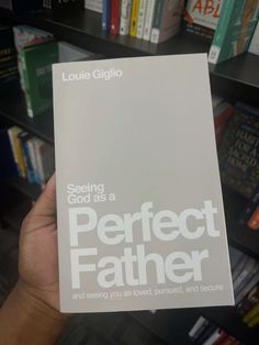 a person holding up a book in front of bookshelves with the title seeing god as a perfect father