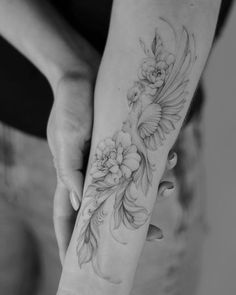 a woman's arm with flowers and leaves on the wrist, in black and white