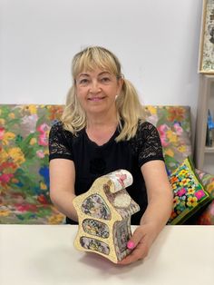 a woman sitting on a couch holding a doll house