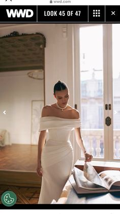 a woman in a white dress is looking at an open book