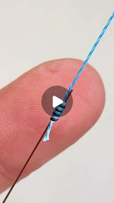 a person holding a blue string with a small white button on it's tip