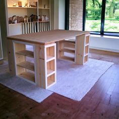 an empty room with a desk and bookcases on the floor in front of a large window