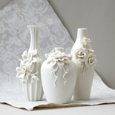 three white vases sitting on top of a table