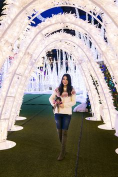 a woman is walking through an archway decorated with lights