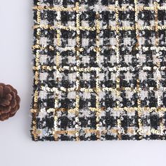 a black and white checkered blanket next to a pine cone on top of a table