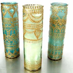 three green vases with gold designs on them sitting next to each other in front of a white background