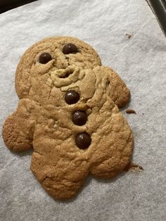 a cookie shaped like a teddy bear sitting on top of baking paper