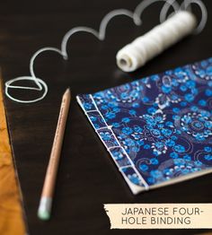 the japanese four - hole binder is next to a pair of scissors and thread