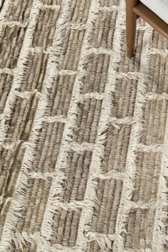 an area rug with fringes on it and a wooden chair in the foreground