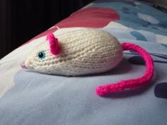 a crocheted toy mouse laying on top of a bed